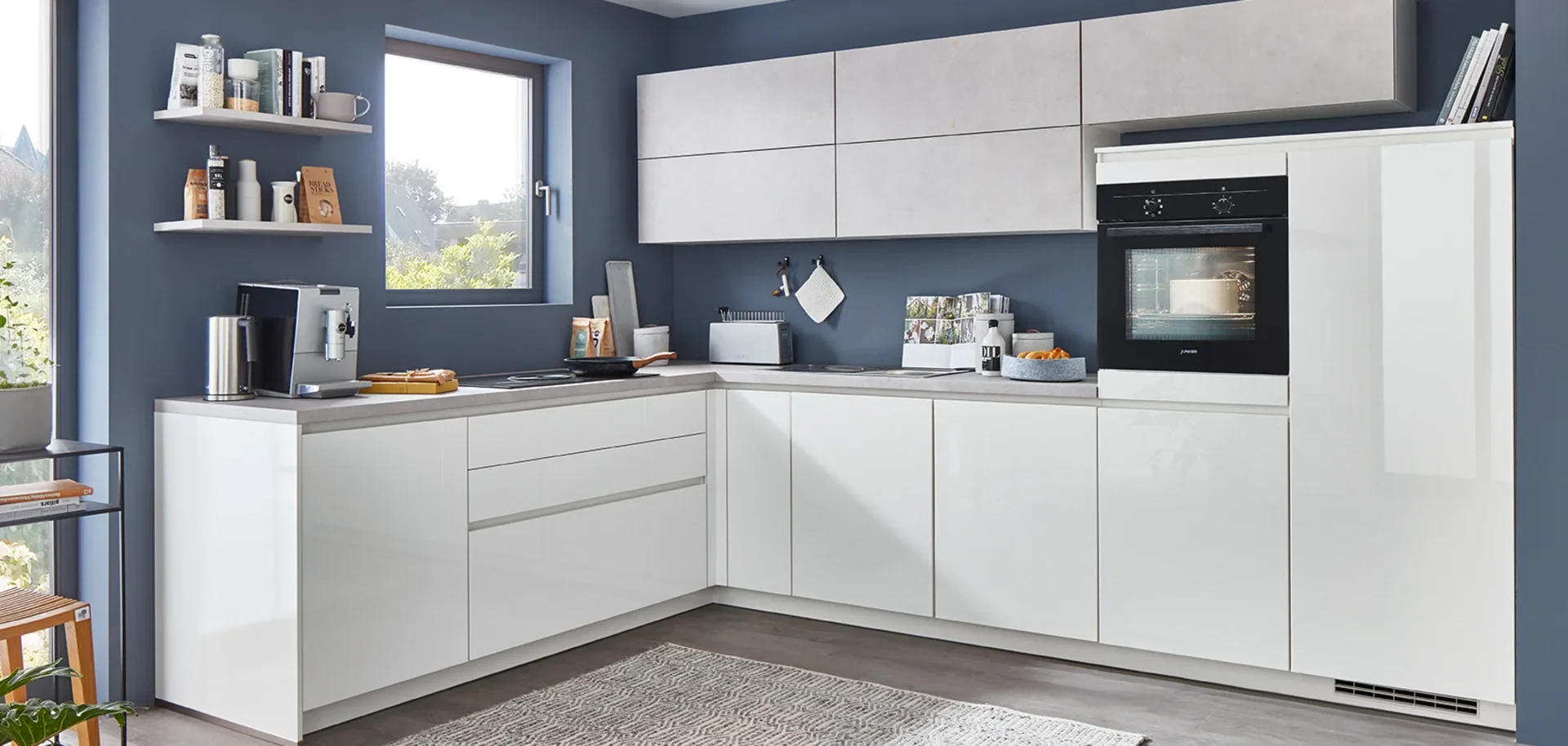 nobilia: Weiße Hochglanz-Küche über Eck in L-Form ohne Insel oder Theke, mit Backofen im Hochschrank vor blauer Wand
